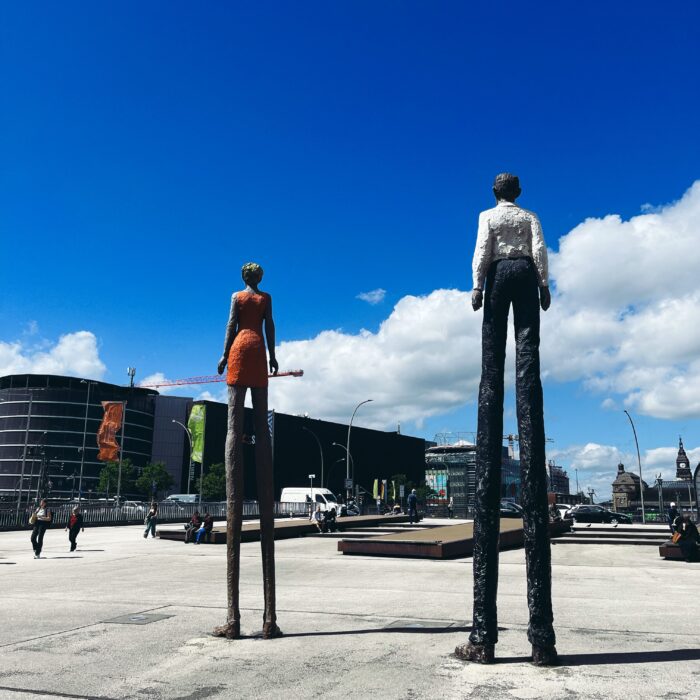 Die Figuren Mann und Frau vom Bildhauer Dtephan Balkenhol vor der Zentralbücherei in Hamburg, im Hintergrund Saturn und der Hauotbahnhof