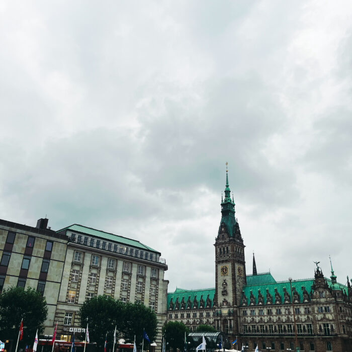 Das Hamburger Rathaus, aus den Arkaden heraus aufgenommen, unter typisch grauem Himmel und hohen Wolken