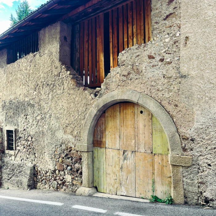 Fassadendetails in Kaltern, ein alter Torbogen, schadhafte Holzelemente in einer alten Mauer