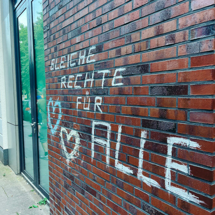 Eine mit Kreide bemalte Ziegelwand, der Schriftzug: "Gleiche Rechte für alle" und zwei Herzen