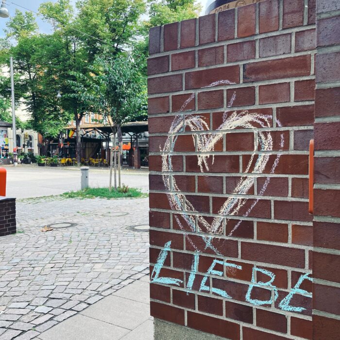 Eine mit Kreide bemalte Ziegelwand, ein großes Herz, unter dem Liebe steht