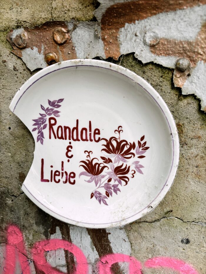 Street-Art, ein an eine Wand geklebter Teller mit der Aufschrift "Randale und Liebe", am Rand fehlt ein Stück