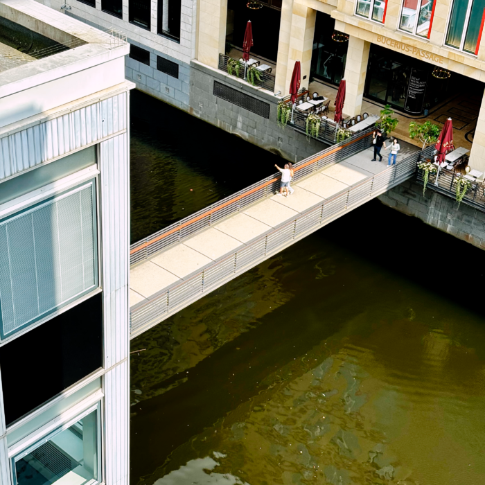 Blick on oben aus einem Fenster heraus auf eine Fußgängerbrücke über den Alsterfleet, Höhe Buceriurs-Forum