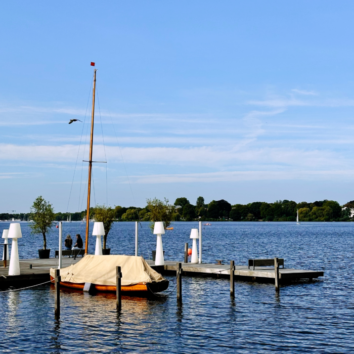 Sommerlicher Nachmittag, ein mit einer Plane zugedecktes Segelboot liegt an einem Außenalstersteg