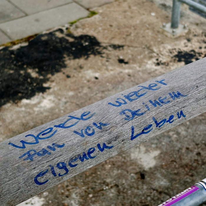 Ein handschriftlicher Satz auf einem Zaun: Werde wieder Fan von Deinem eigenen Leben