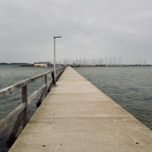 Ein Steg am Strand von Wackerballig, im Hintergrund der Mastenwald eines ´Segelclubs