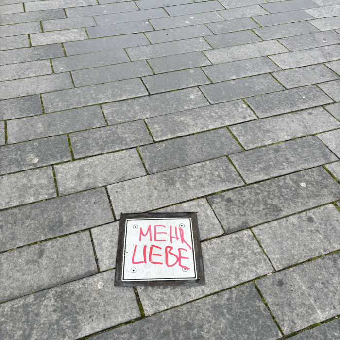 Ein Graffiti auf einer Bodenplatte: "Mehr Liebe"