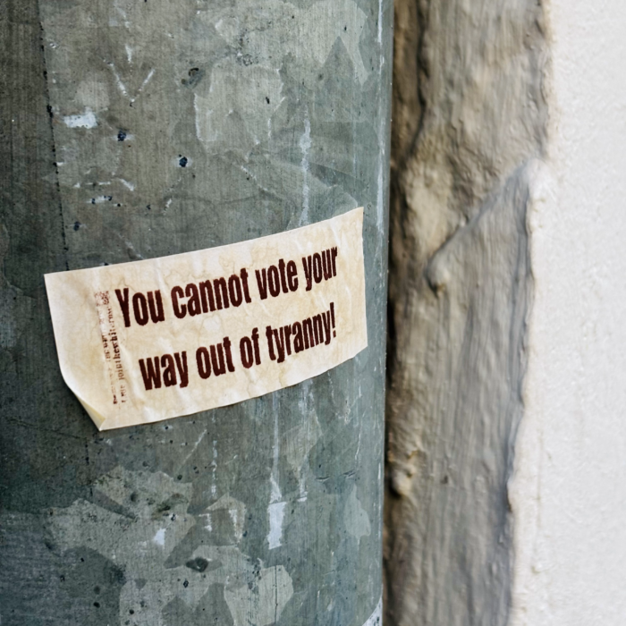 Ein kleiner Sticker an einem Regenabflussrohr: You cannot vote your way out of tyranny