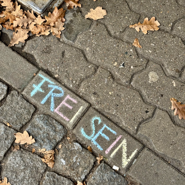 Bunte Kreideschrift auf dem Pflaster: "Frei Sein"